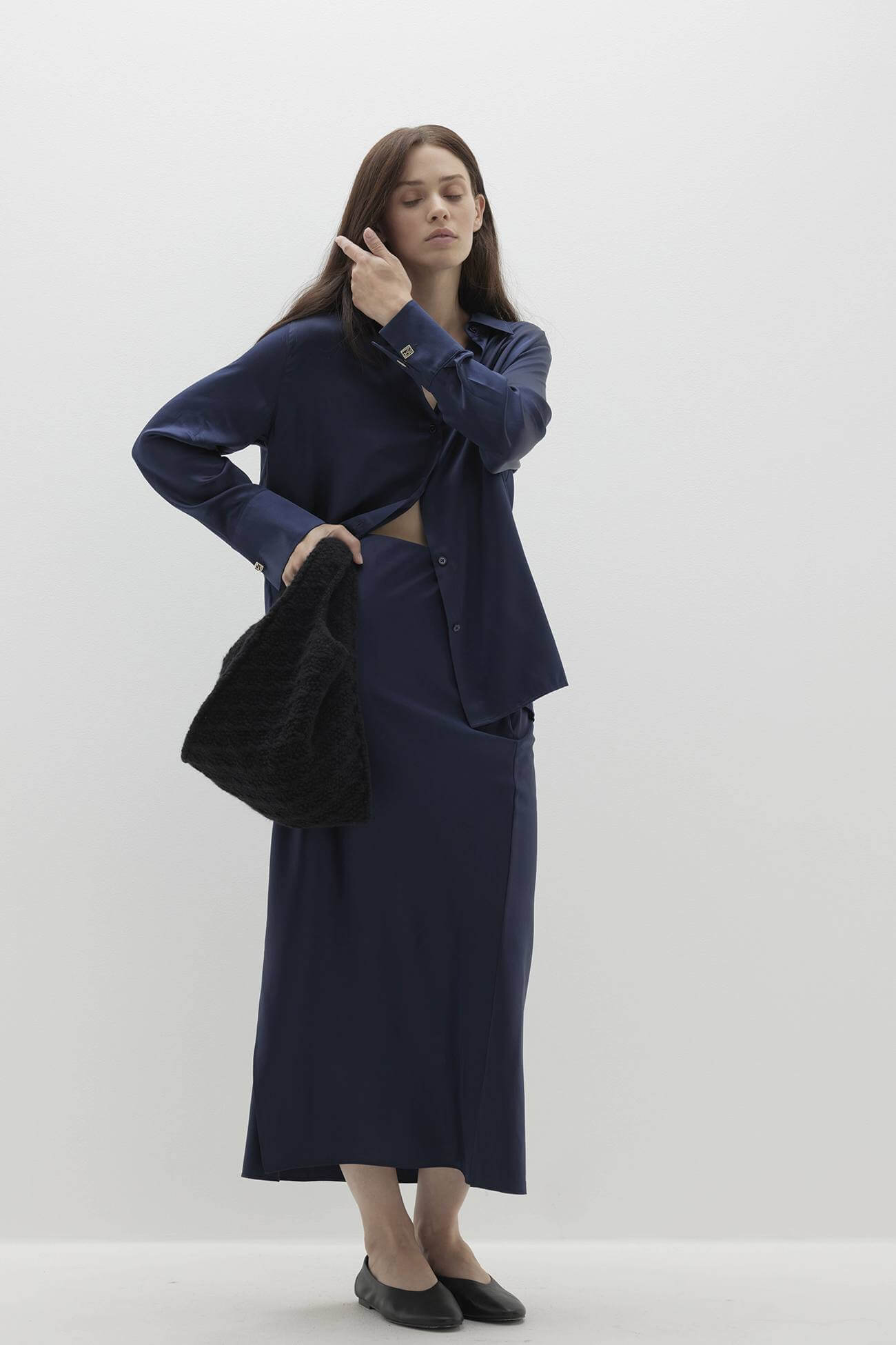 Fashion model in a navy outfit showcasing chic Accessories against a minimalistic background.