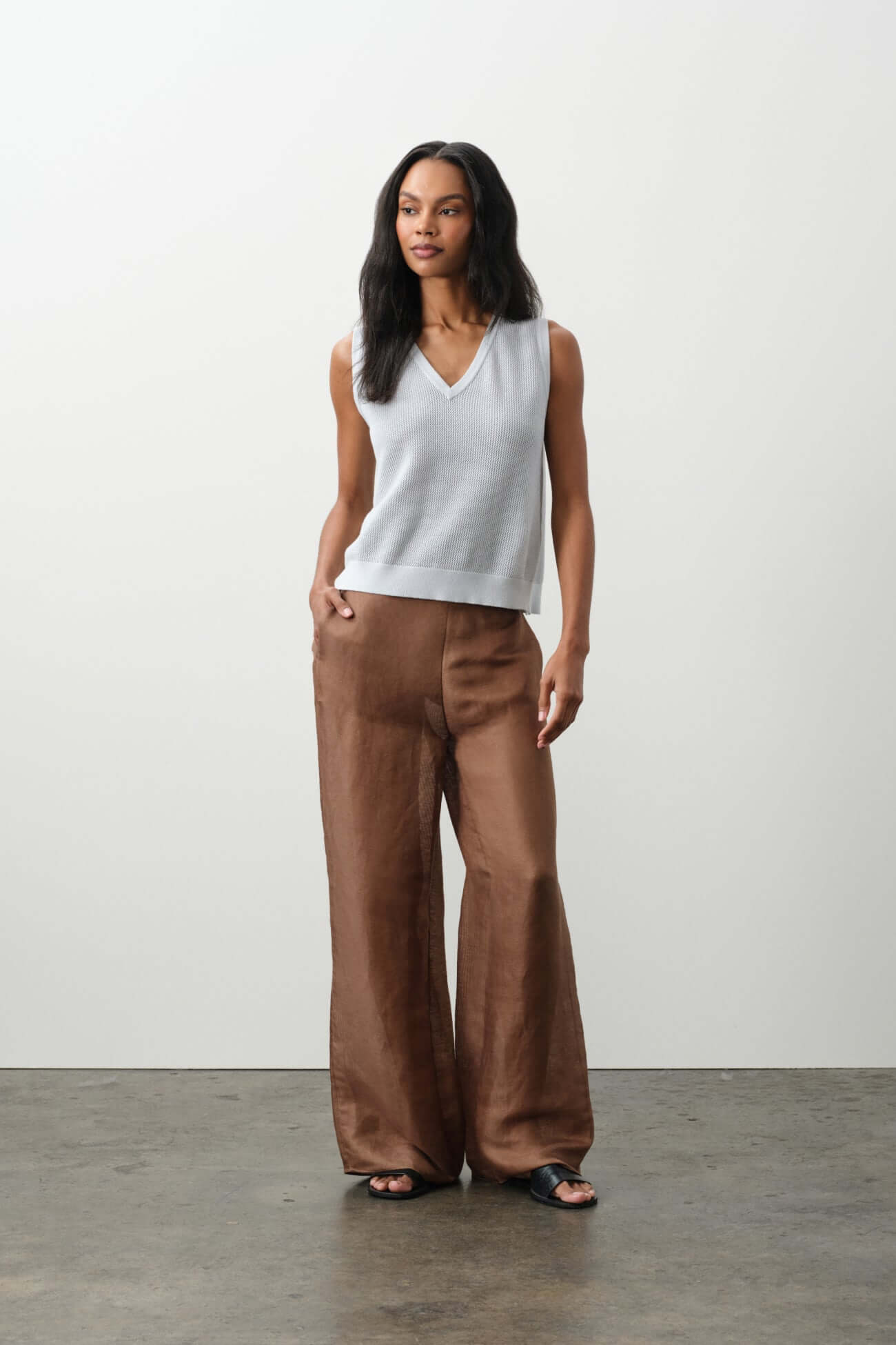 Model wearing a stylish light gray top and brown wide-leg pants from the Bottoms collection.